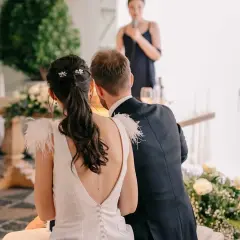 Novia con coleta baja adornada con horquillas, ideal para peinados para boda civil. El novio, de traje oscuro, la acompaña.