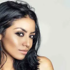 Mujer con piel morena, ojos marrones y un color de pelo azabache que resalta su belleza natural.