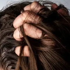 Mano revolviendo cabello oscuro. ¿Es mejor teñirse con el pelo sucio o limpio?