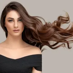 Mujer con cabello castaño ondulado y largo, con un vestido negro. ¿Buscas como quitar el tinte del pelo?