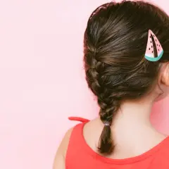 Peinados para niñas: una trenza lateral con un pasador de sandía, ideal para un día soleado.