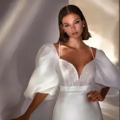 Elegante peinado para damas de boda, con un vestido blanco de escote pronunciado y mangas abullonadas.