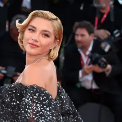 Peinados melena corta boda: rubia con ondas suaves y un vestido negro brillante, lista para un evento especial.