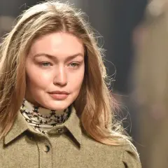 Modelo con cabello rubio y mechas blancas, viste una chaqueta verde y un pañuelo estampado.