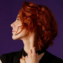 Mujer de 40 con cabello rizado y pelirrojo, un corte moderno y favorecedor.
