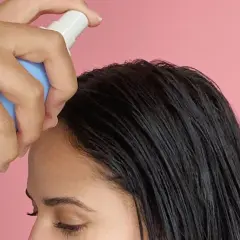 Una mano aplica sérum en el cabello oscuro. Descubre para qué sirve el sérum pelo y luce una melena radiante.
