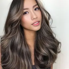 Mujer con cabello castaño oscuro con mechas balayage en tonos miel y ceniza. Las mechas lucen naturales y bien integradas, creando un efecto de profundidad y dimensión. La pregunta de cuanto duran las mechas es clave para mantener este look.