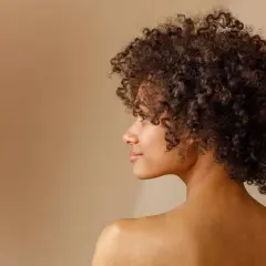 Perfil de una mujer con un espectacular pelo afro, rizos definidos y un rostro sereno.