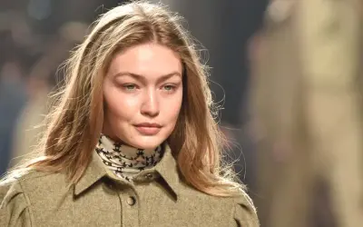 Modelo con cabello rubio y mechas blancas, viste una chaqueta verde y un pañuelo estampado.