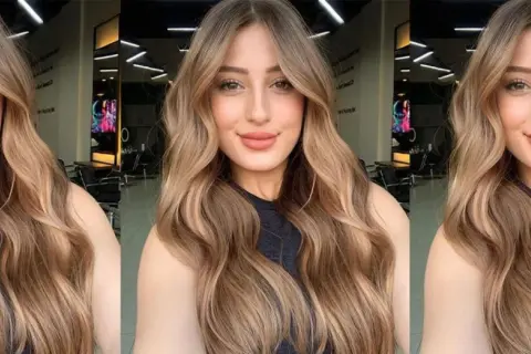 Mujer con cabello largo y ondulado con mechas balayage en tonos miel y caramelo.