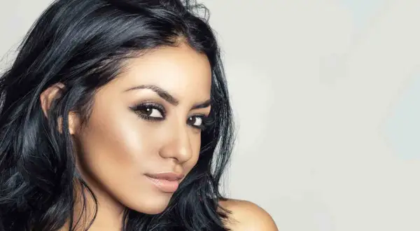 Mujer con piel morena, ojos marrones y un color de pelo azabache que resalta su belleza natural.