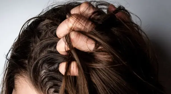Mano revolviendo cabello oscuro. ¿Es mejor teñirse con el pelo sucio o limpio?