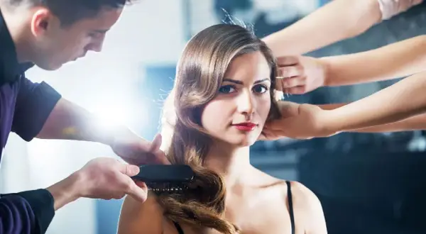 Manicuristas dan forma a las ondas al agua en el cabello de una mujer, creando un look elegante.