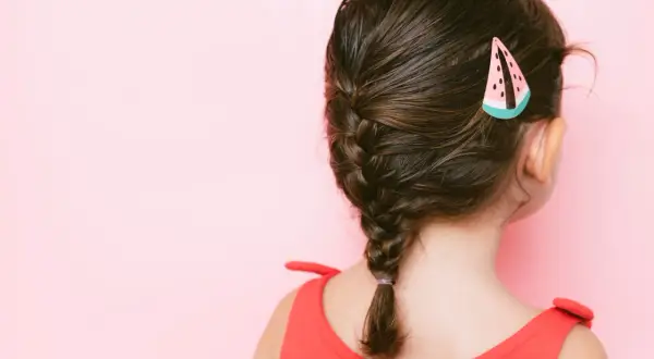 Peinados para niñas: una trenza lateral con un pasador de sandía, ideal para un día soleado.