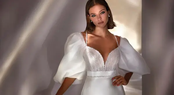 Elegante peinado para damas de boda, con un vestido blanco de escote pronunciado y mangas abullonadas.