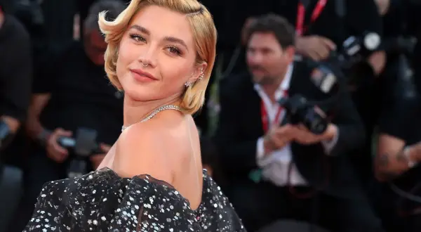 Peinados melena corta boda: rubia con ondas suaves y un vestido negro brillante, lista para un evento especial.