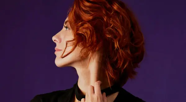 Mujer de 40 con cabello rizado y pelirrojo, un corte moderno y favorecedor.