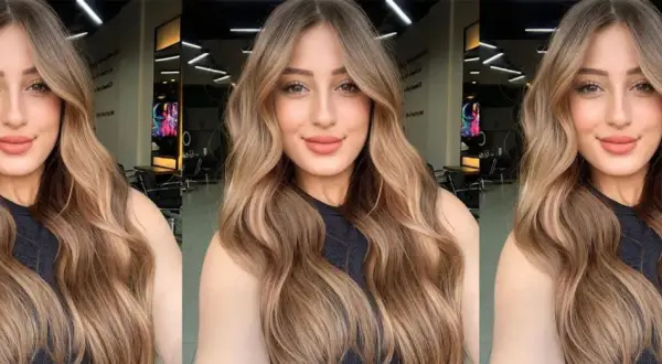 Mujer con cabello largo y ondulado con mechas balayage en tonos miel y caramelo.