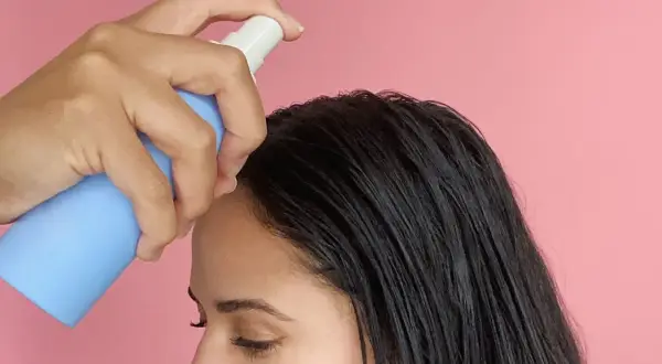 Una mano aplica sérum en el cabello oscuro. Descubre para qué sirve el sérum pelo y luce una melena radiante.