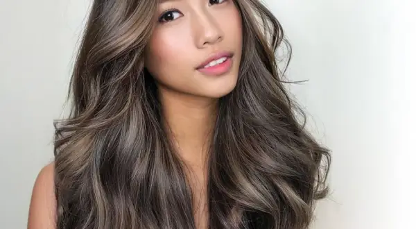 Mujer con cabello castaño oscuro con mechas balayage en tonos miel y ceniza. Las mechas lucen naturales y bien integradas, creando un efecto de profundidad y dimensión. La pregunta de cuanto duran las mechas es clave para mantener este look.