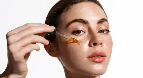 Una mujer aplica un sérum con ácido salicílico y vitamina C en su rostro.