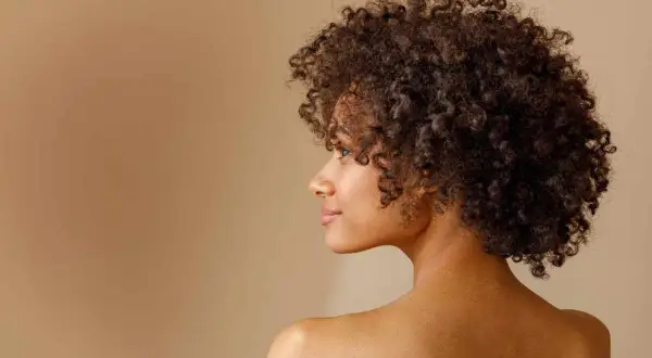 Perfil de una mujer con un espectacular pelo afro, rizos definidos y un rostro sereno.