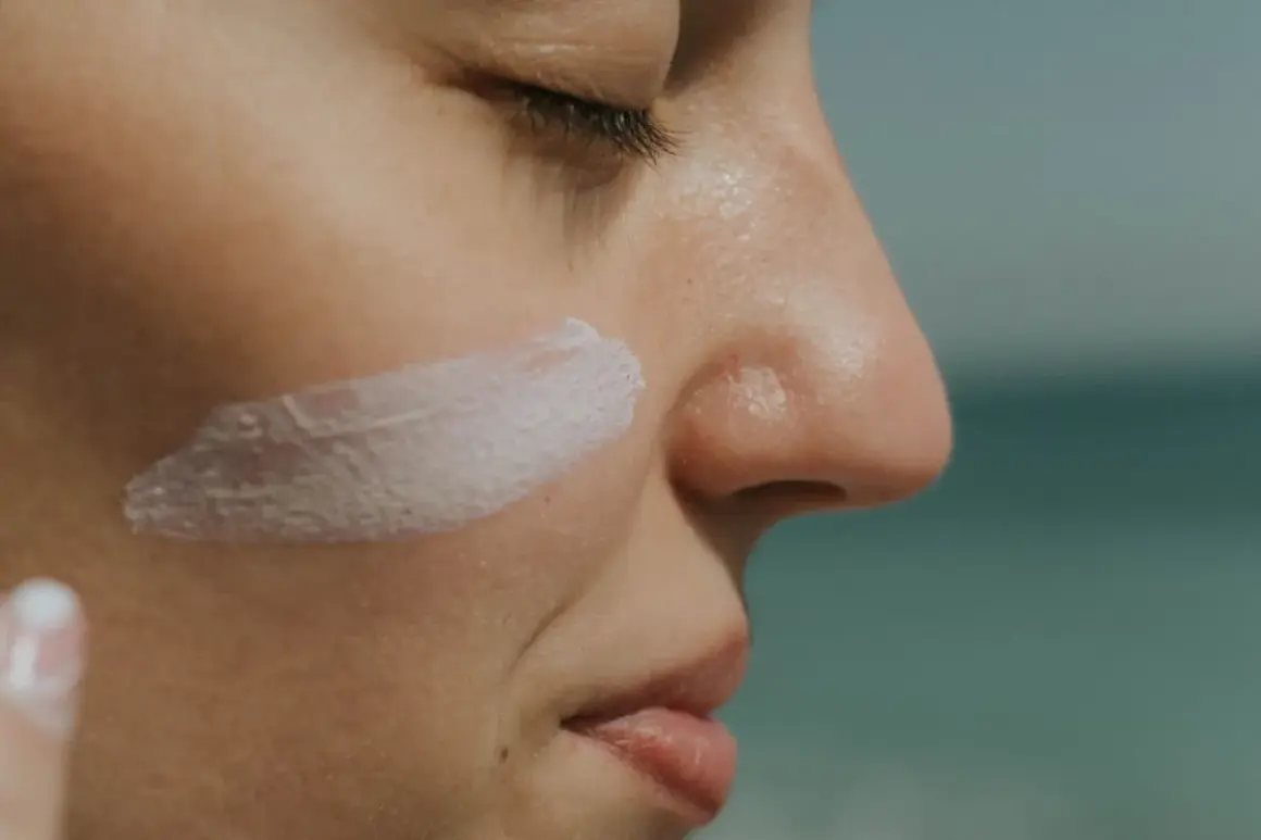 Protección solar: ¿SPF qué es? Crema blanca aplicada en la mejilla de una persona, con el mar al fondo.