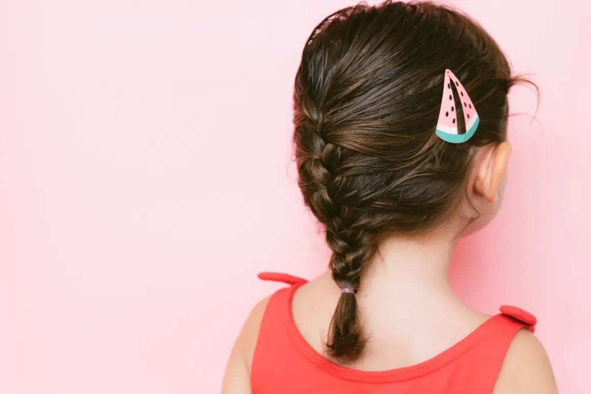 Peinados para niñas: una trenza lateral con un pasador de sandía, ideal para un día soleado.
