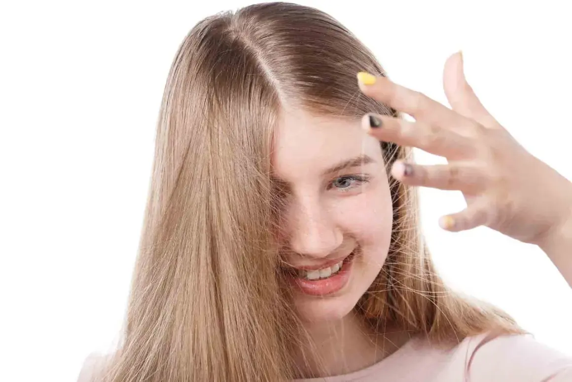 Chica sonriente con cabello rubio que se electrifica. Descubre cómo quitar la electricidad del pelo para un look suave.