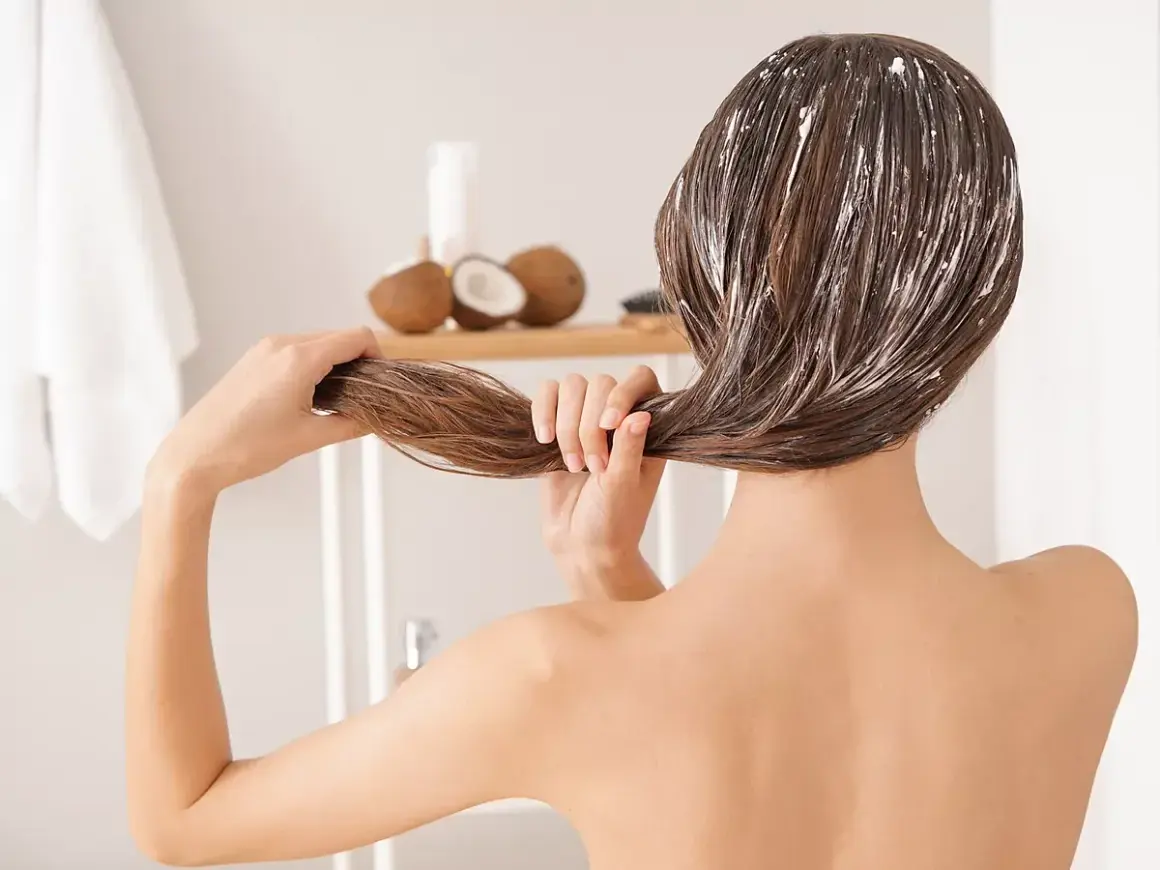 Mujer aplicándose mascarilla capilar con aceite de coco. Descubre para qué sirve el aceite de coco para un cabello radiante.