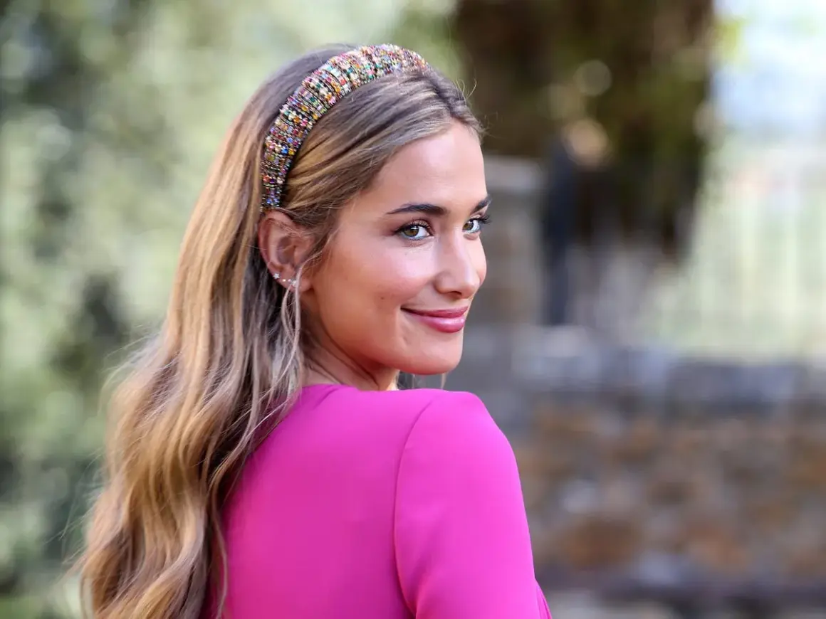Joven sonriente con un peinado juvenil para boda, luciendo una diadema de pedrería y un vestido fucsia.