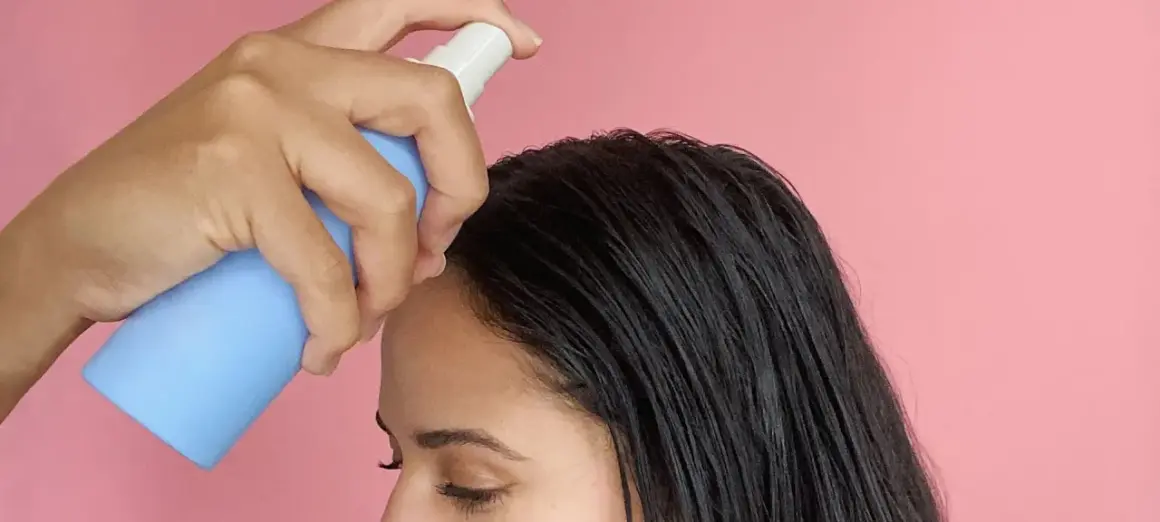 Una mano aplica sérum en el cabello oscuro. Descubre para qué sirve el sérum pelo y luce una melena radiante.
