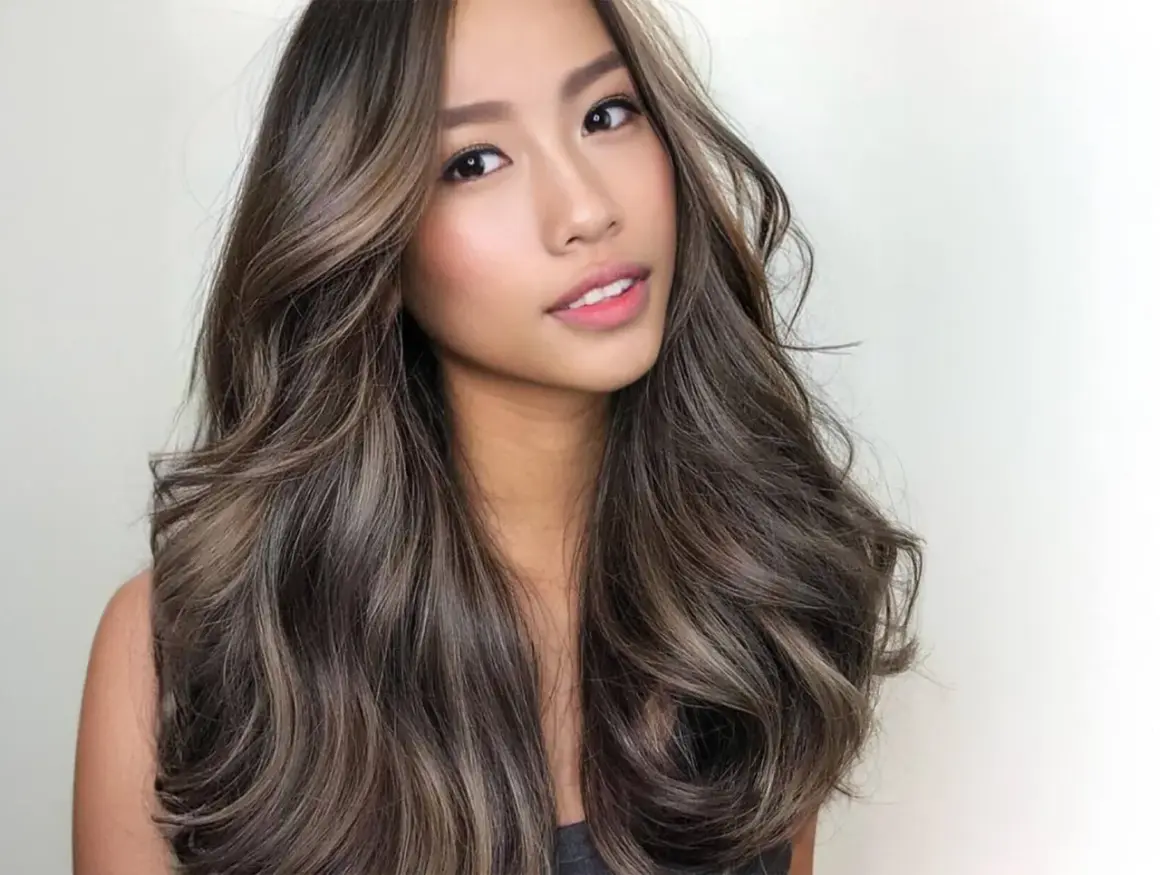 Mujer con cabello castaño oscuro con mechas balayage en tonos miel y ceniza. Las mechas lucen naturales y bien integradas, creando un efecto de profundidad y dimensión. La pregunta de cuanto duran las mechas es clave para mantener este look.