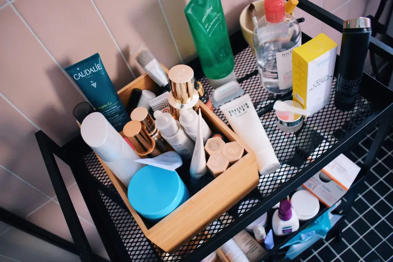 Estante con productos de cuidado de la piel, incluyendo un tubo de Caudalie y un sérum con niacinamida y vitamina C.