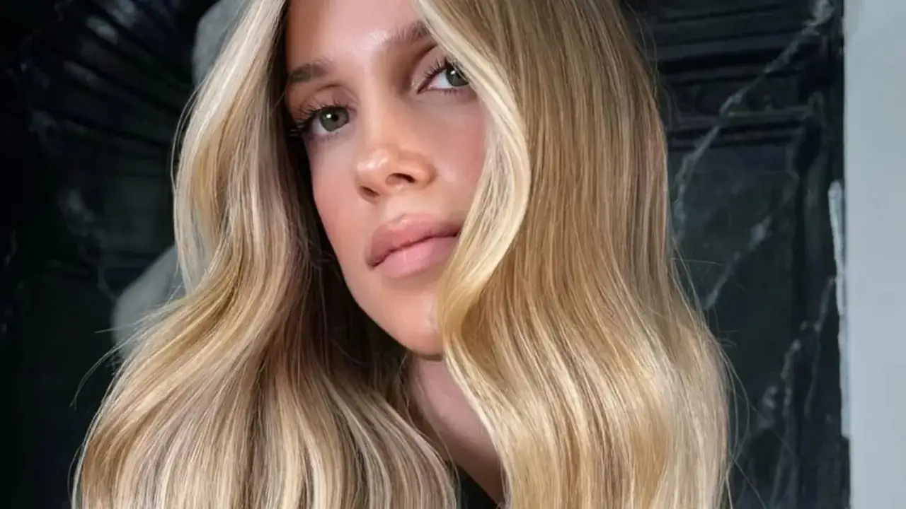 Mujer con cabello rubio mantequilla ondulado, con reflejos dorados y mechas claras.