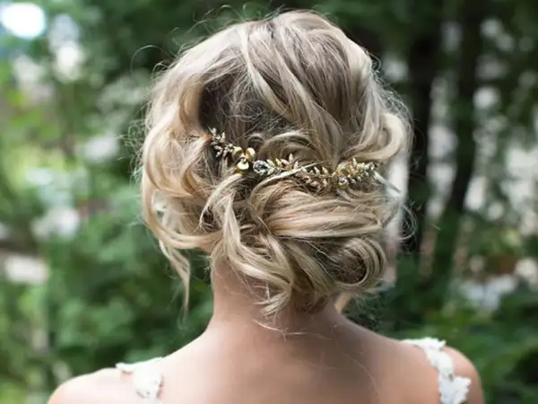 Recogido con trenzas boda, adornado con una delicada diadema dorada con detalles de pedrería.
