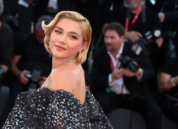 Peinados melena corta boda: rubia con ondas suaves y un vestido negro brillante, lista para un evento especial.