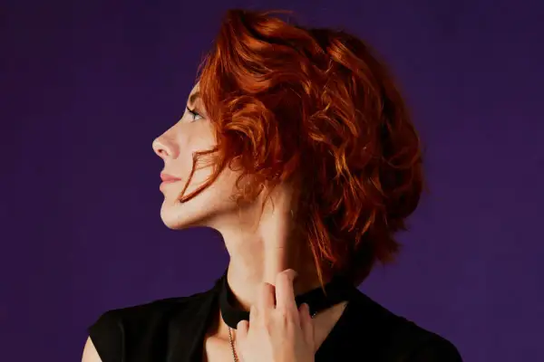 Mujer de 40 con cabello rizado y pelirrojo, un corte moderno y favorecedor.