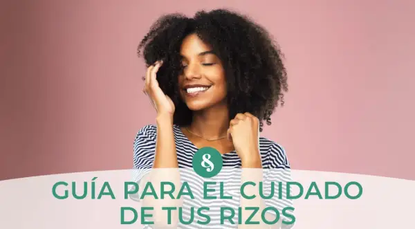 Mujer sonríe con ojos cerrados, tocando su pelo rizado. Guía para el cuidado de tus rizos, aprendiendo como hidratar el pelo rizado.