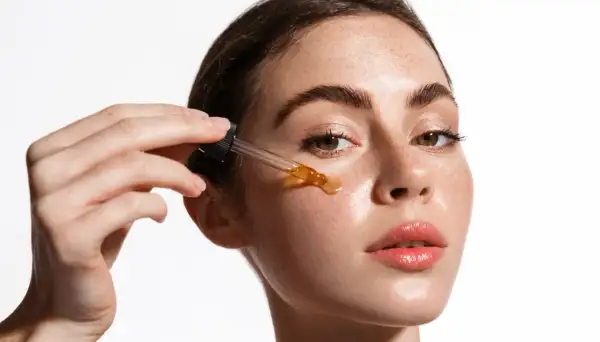 Una mujer aplica un sérum con ácido salicílico y vitamina C en su rostro.